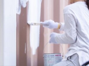 DIY塗装で鉄製の外壁を塗装している女性